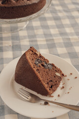 Chocolate pie on a white plate with a spoon on the blue checkered tablecloth. Vintage style. Selective focus