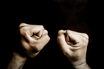Fist isolated on black. Agression background. Artistic light male hands point of view. Fighting...