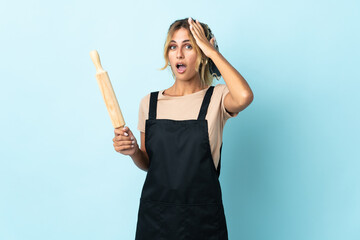 Young blonde Uruguayan cooking woman isolated on blue background doing surprise gesture while...