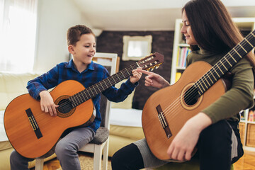 Brother and sister playing guitar at home and having fun.