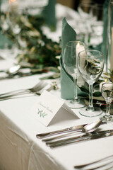 Elegant table setting at the restaurant. Wedding banquet with floral decoration on table, cards, glasses and cutlery closeup