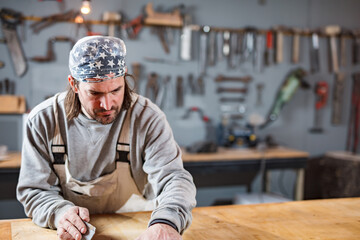 Male carpenter working on old wood in a retro vintage workshop.