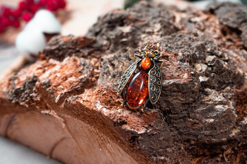 Suspension in the form of a beetle of bronze and amber on a wooden background