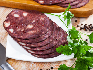 European cuisine blood pudding served with parley on white plate on wooden table