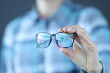 Glasses with black optics are held in hand