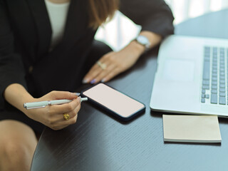 Fototapeta premium Businesswoman in black suit working with smartphone and laptop on the table in meeting room