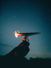 Human arm with burning paper airplane in the sky