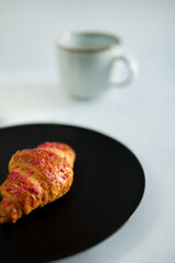 croissant with raspberries on a black plate on a white background. Parisian style of food.