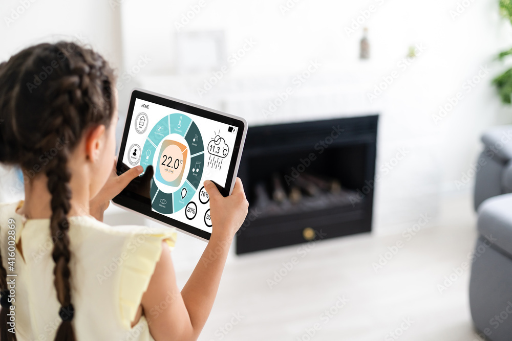 Poster shot of little girl using a domotic system with her digital tablet while standing at home.