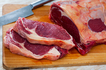 Obraz premium Sliced beef pieces on wooden board with knife