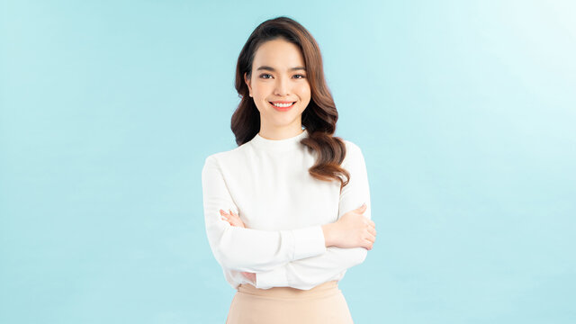 Image of cheerful woman in basic t-shirt smiling at camera while standing with arms crossed isolated over blue background