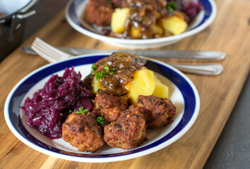 Meatballs with red cabbage, potatoes and onion sauce on a plate