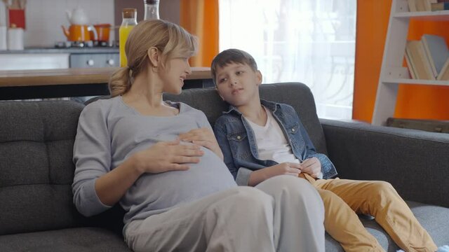 A little boy loves his pregnant mother's tummy and chats.Little boy touching abdomen of his pregnant mother. Mother child, brotherly love.