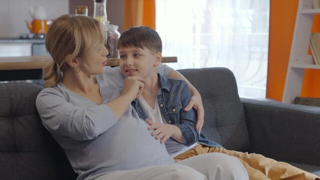 Little boy touching abdomen of his pregnant mother.A little boy loves his pregnant mother's tummy and chats. Little boy touching abdomen of his pregnant mother