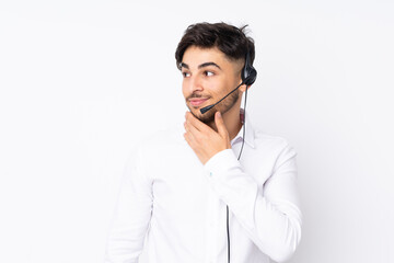 Telemarketer Arabian man working with a headset isolated on white background thinking an idea