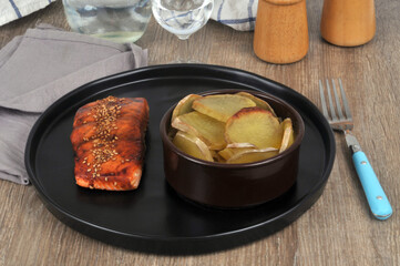 Saumon laqué avec du sésame et un gratin de pommes de terre servi dans une assiette