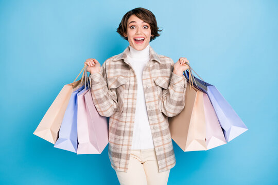Photo of excited girl hold shop packages open mouth wear checkered coat isolated blue color background