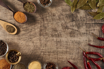 wooden spoons with spices bay leaves  bowls of spices and dried red pepper on a wooden surface