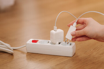 Woman pluging the wire into white extension cord. Close up of female hand put cabel