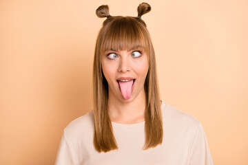 Photo portrait of childish crazy girl showing tongue grimacing wearing t-shirt isolated on pastel beige color background