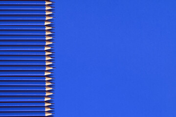 blue pencils stacked in a row on a blue background