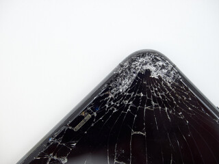 Angle of modern space grey smartphone with a broken glass display and damaged curved body close-up isolated on white background