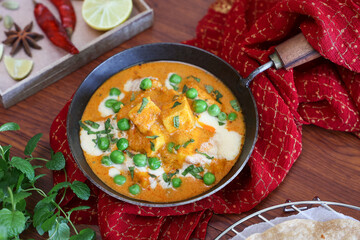 Matar Paneer curry, paneer butter masala recipe made using cottage cheese, green peas, served in a bowl.  Delhi, Rajasthan India. Indian veg curry wooden background. side dish of Roti, Chapati, naan