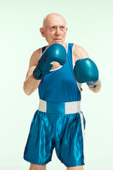 Senior man wearing sportwear boxing isolated on studio background. Caucasian male model in great...