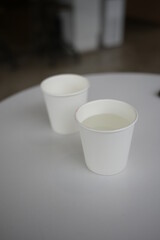 two white paper cups in cafe coffee table with mobile phone