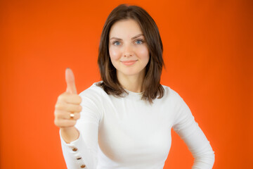 Happy young woman giving thumb up on ocher background