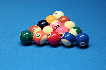 A pyramid of billiard balls on a blue cloth. Image with selective focus.