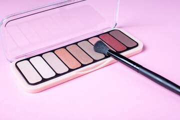 Eyeshadow palette for make up on pink background with copyspace close up