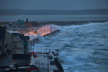 Giant waves and violent storm jumping over the pier in the seaside town of Tramore, Waterford,...