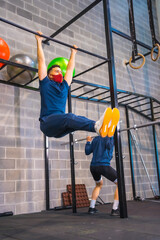 Two athletes performing strength exercises in the gym in the coronavirus pandemic, a new normal. With protective face mask