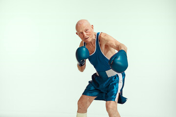 Match. Senior man wearing sportwear boxing on studio background. Caucasian male model in great...