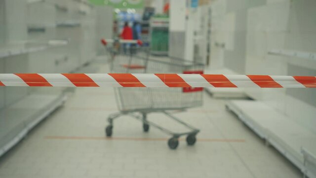 barrage tape on the background of empty store shelves and a shopping cart