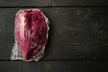 Roast beef in  vacuum packed, on black wooden table background, top view flat lay,  with copy space...