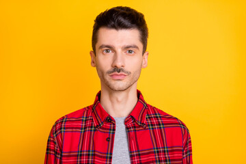 Photo of serious confident young man wear red checkered shirt isolated yellow color background
