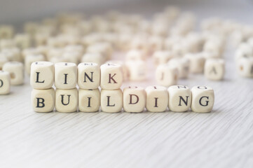 Link building words written in wooden cubes next to a pile of other letters. Backlinks concept,...