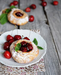 homemade puff pastry buns stuffed with cherry side view on old wooden table background closeup. Selective focus