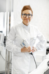 A portrait of cheerful cosmetologist holding Ultrasound lifting device for a procedure on the face in beauty clinic. Anti-age and wellness concept. 