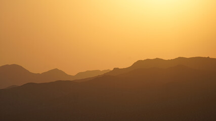 A glowing sunset sky over a mountain range in the Mojave National Preserve