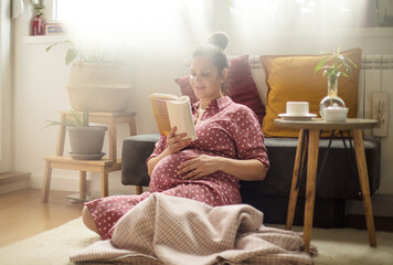 Pregnant woman relaxing at home and reading book.