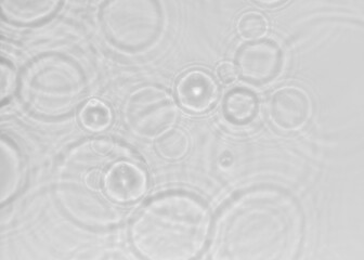 White shadow texture of the sun light refraction in concentric circular waves from drops falling on...