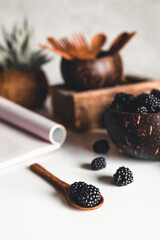Ripe blackberries with leaves in a bowl on a wooden board on a dark background