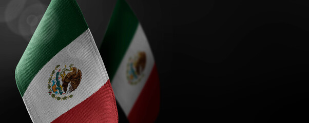 Small national flags of the Mexico on a dark background