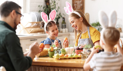 Happy family painting Easter eggs in light kitchen