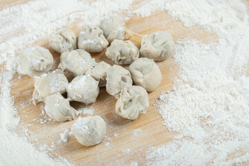 Fototapeta na wymiar Raw dumplings with flour on a wooden board