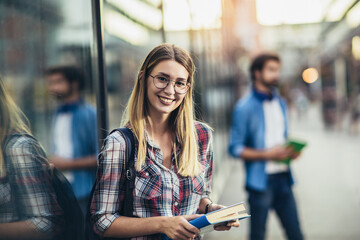 Happy young university students friends studying with books at university