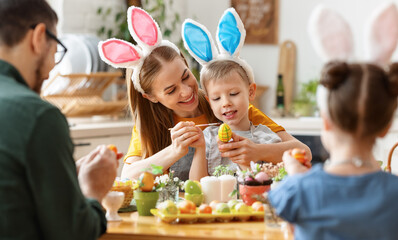 Happy family painting Easter eggs in light kitchen